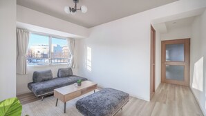A modern living room with a sofa set, a coffee table, and a small table with a plant. - E-US NAEBO 203 (Sapporo)