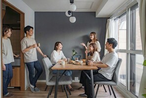 A modern dining area with a wooden table, grey chairs, and a grey accent wall. - E-US NAEBO 203 (Sapporo)