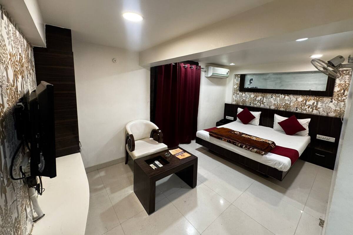 Een hotelkamer met een bed, een bureau, een stoel, een televisie en een airconditioning.