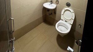 A small, well-lit bathroom with a toilet, sink, and shower. - HOTEL BANJARA (Bhopal)