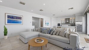 Ein modernes Wohnzimmer mit einem grauen Ecksofa, einem Holztisch und einem Bild von einer Strandlandschaft.
