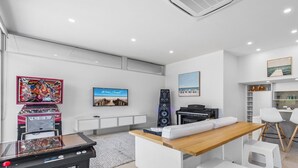 Ein modernes Zimmer mit Flachbildfernseher, einem Klavier, einer Couch und einem Billardtisch.