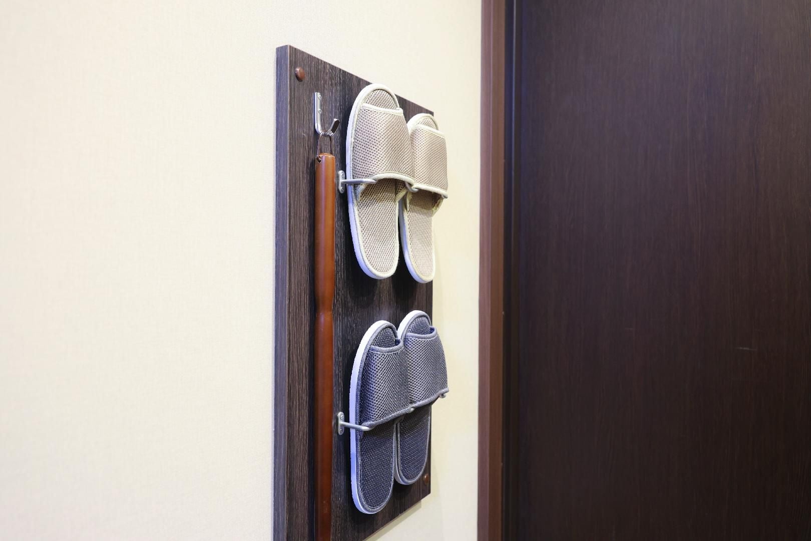 A wall-mounted shoe rack with two pairs of shoes.