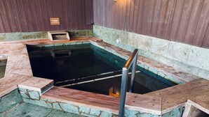 Een hottub met een houten bankje en een bordje dat aangeeft dat het een koud bad is.
