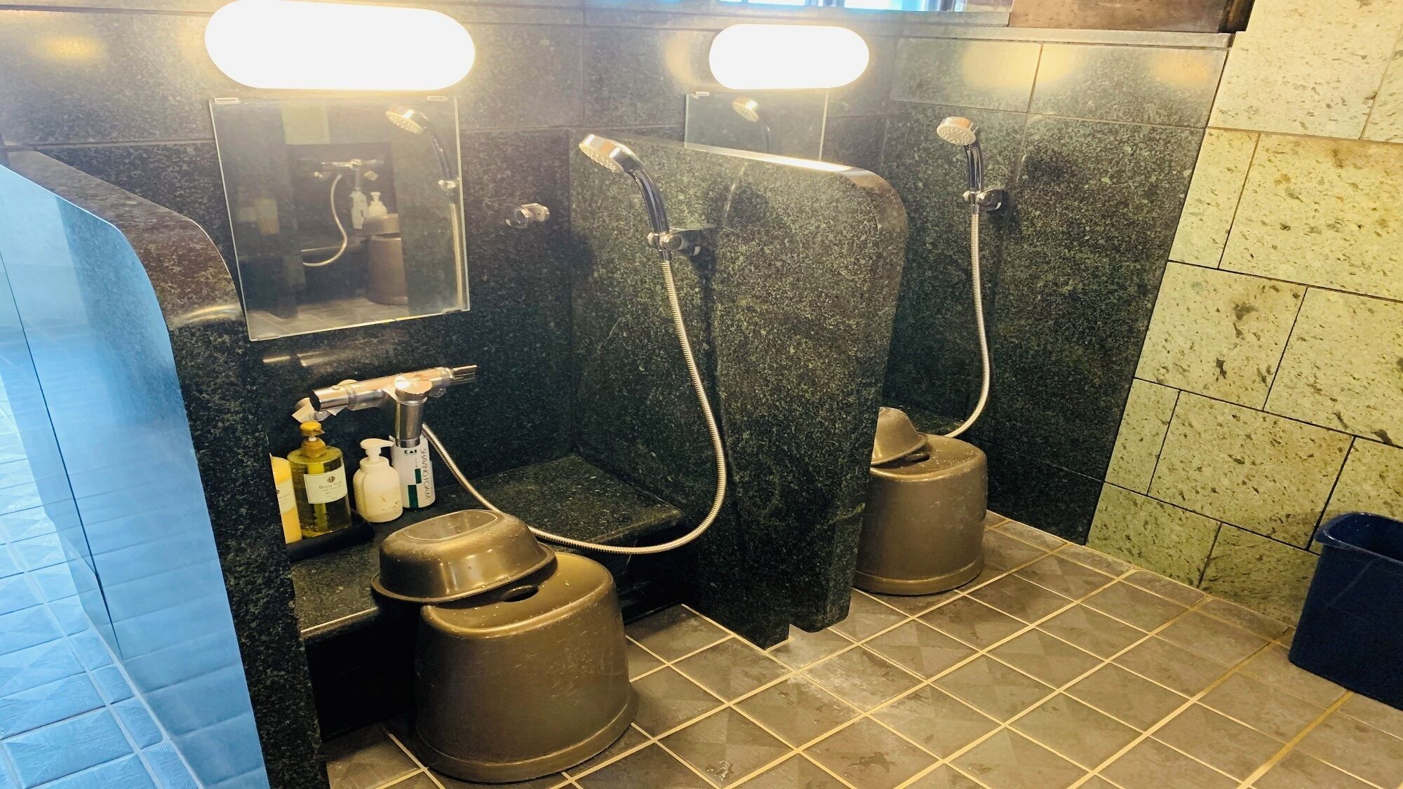 A public restroom with two sinks, a mirror, and a shelf with toiletries.