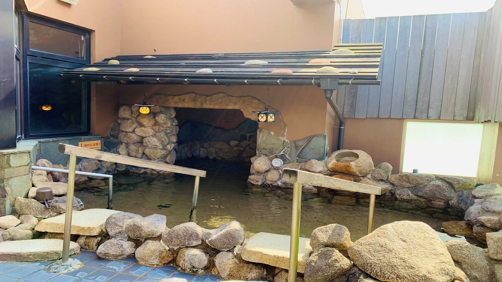Un arco de piedra que conduce a un espacio cubierto con un muro de piedra y un pequeño estanque.
