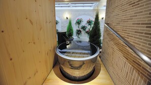 Een bubbelbad in een smalle ruimte met houten wanden en een vloer van baksteen.