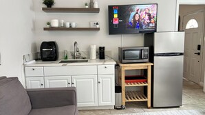 Una cucina moderna con forno a microonde integrato, macchina del caffè e televisore montato a parete.