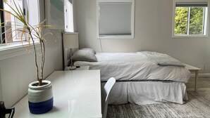 Una camera da letto con un letto, un comodino, una lampada e una pianta in vaso.