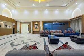 Un vestíbulo de hotel con mostrador de recepción, zona de estar y un cartel que dice 'DAKSHIN'.