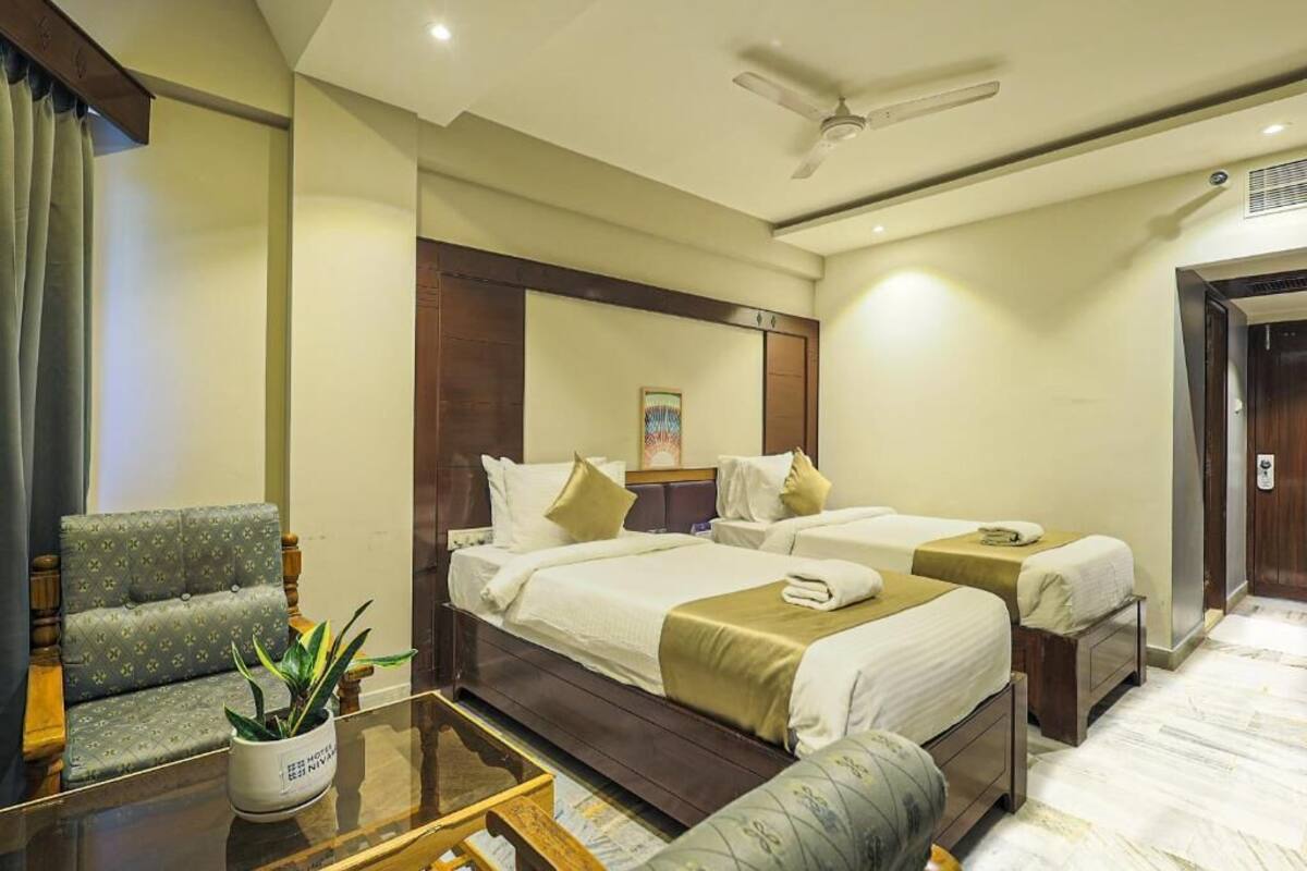 Une chambre d’hôtel avec deux lits, un canapé, une table basse et un ventilateur de plafond.
