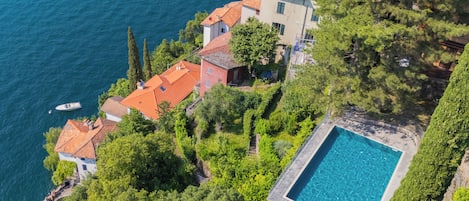 A coastal property with a swimming pool, terraced houses, and boats on the water.