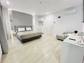 A modern hotel room with a bed, bedside table, and a desk with a lamp. - AVA Urban Suites (Turda)