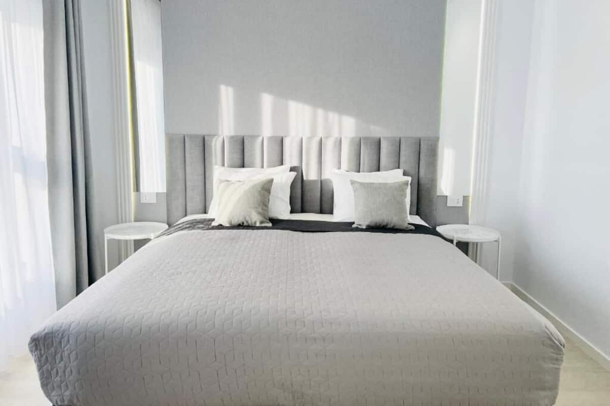 A modern bedroom with a large bed, two bedside tables, and a neutral color scheme.