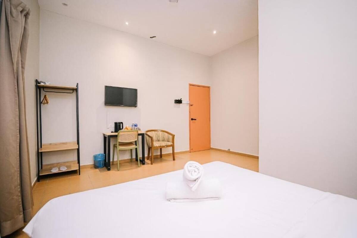Una habitación de hotel con una cama, un escritorio con silla, un televisor y una puerta.