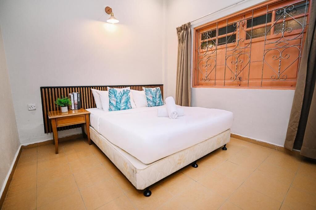 A neatly arranged bedroom with a bed, bedside table, and a window with decorative iron bars.