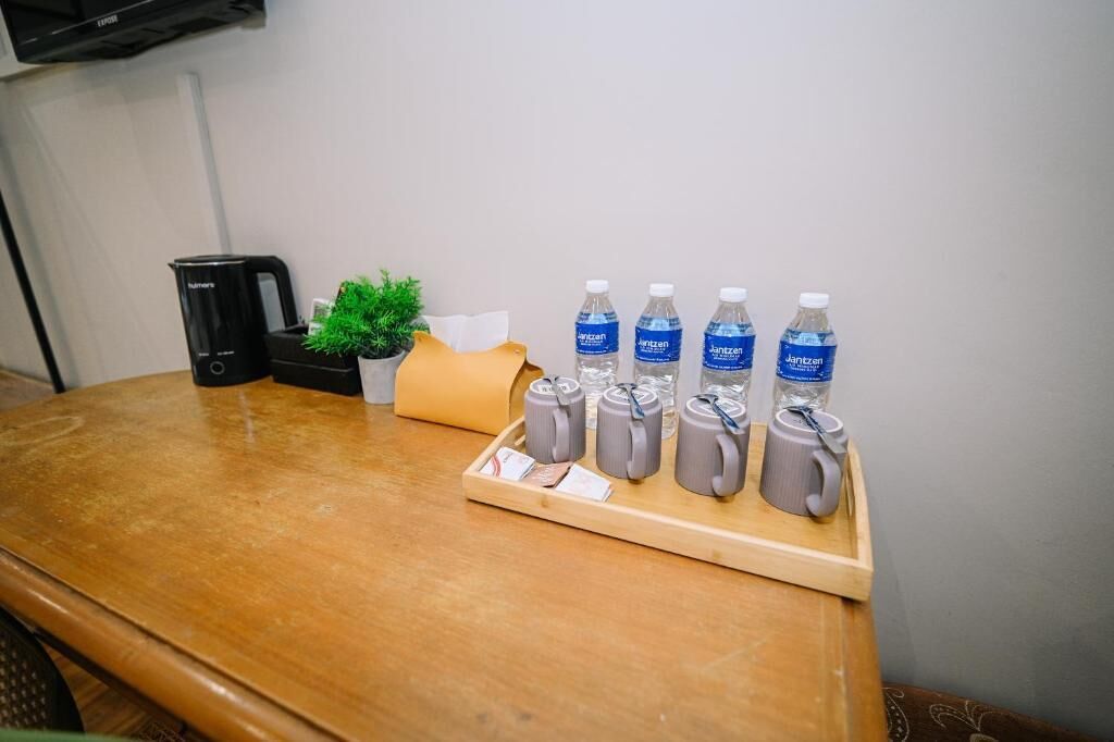 A wooden table with a tray holding water bottles, a coffee maker, and a small plant.