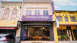 Un hotel con toldo morado, un letrero que dice 'Swing & Pillows' y una entrada visible.