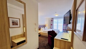 A hotel room with a bed, a desk, a TV, and a mirror. - Blume Hausach I Hotel & Restaurant (Hausach)