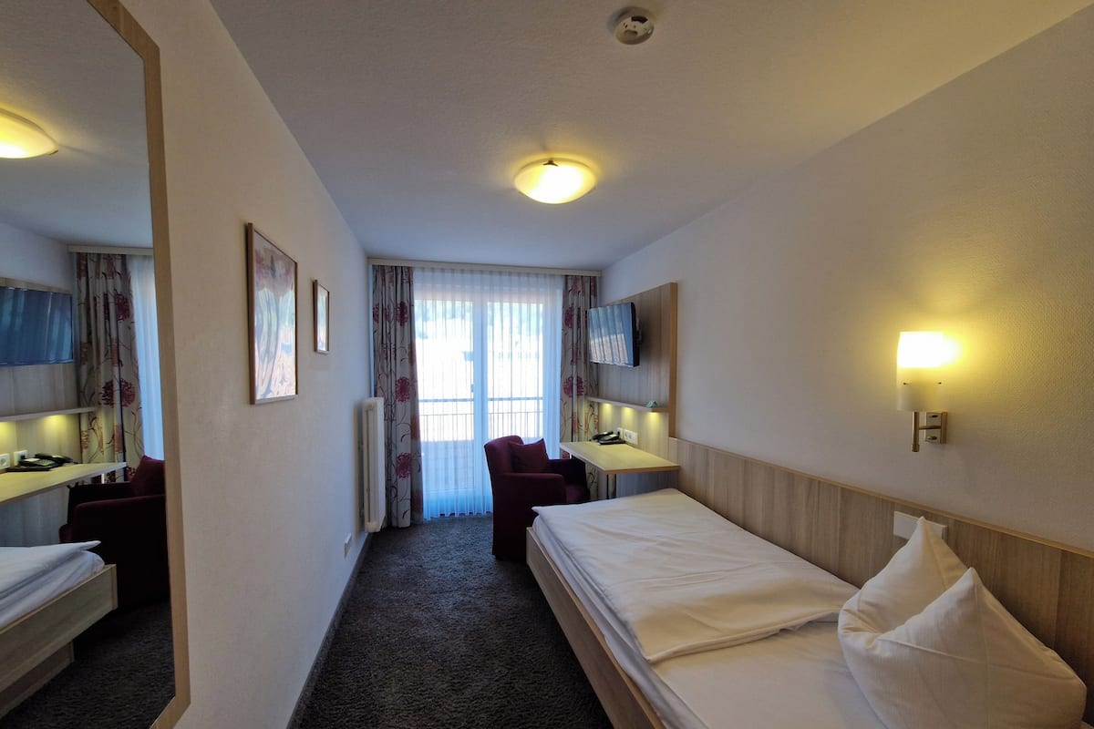 Une chambre d’hôtel équipée d’un lit, d’un bureau, d’une chaise, d’une télévision et d’une fenêtre avec des rideaux.