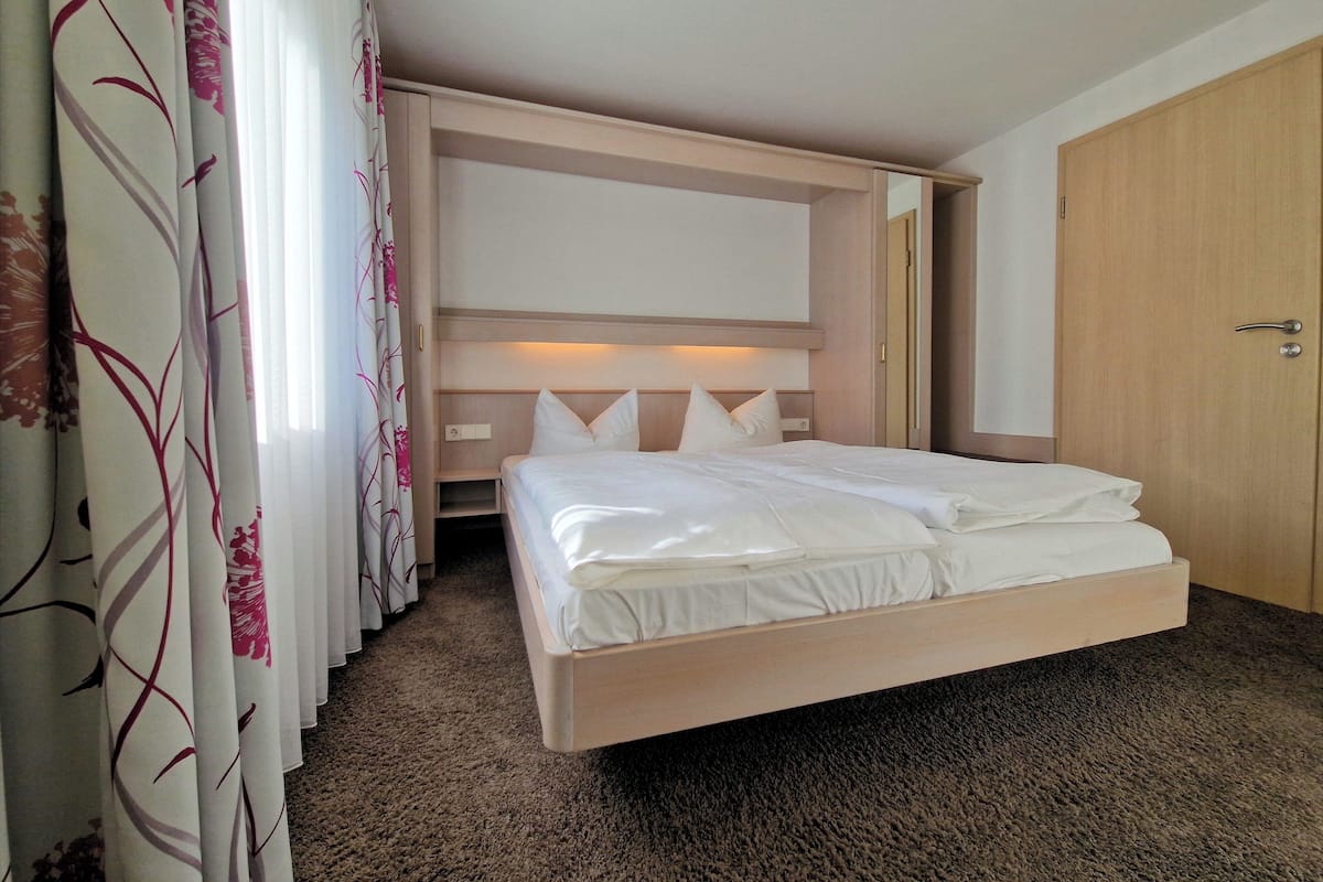 Une chambre d’hôtel avec un grand lit, une armoire et un téléviseur intégré.