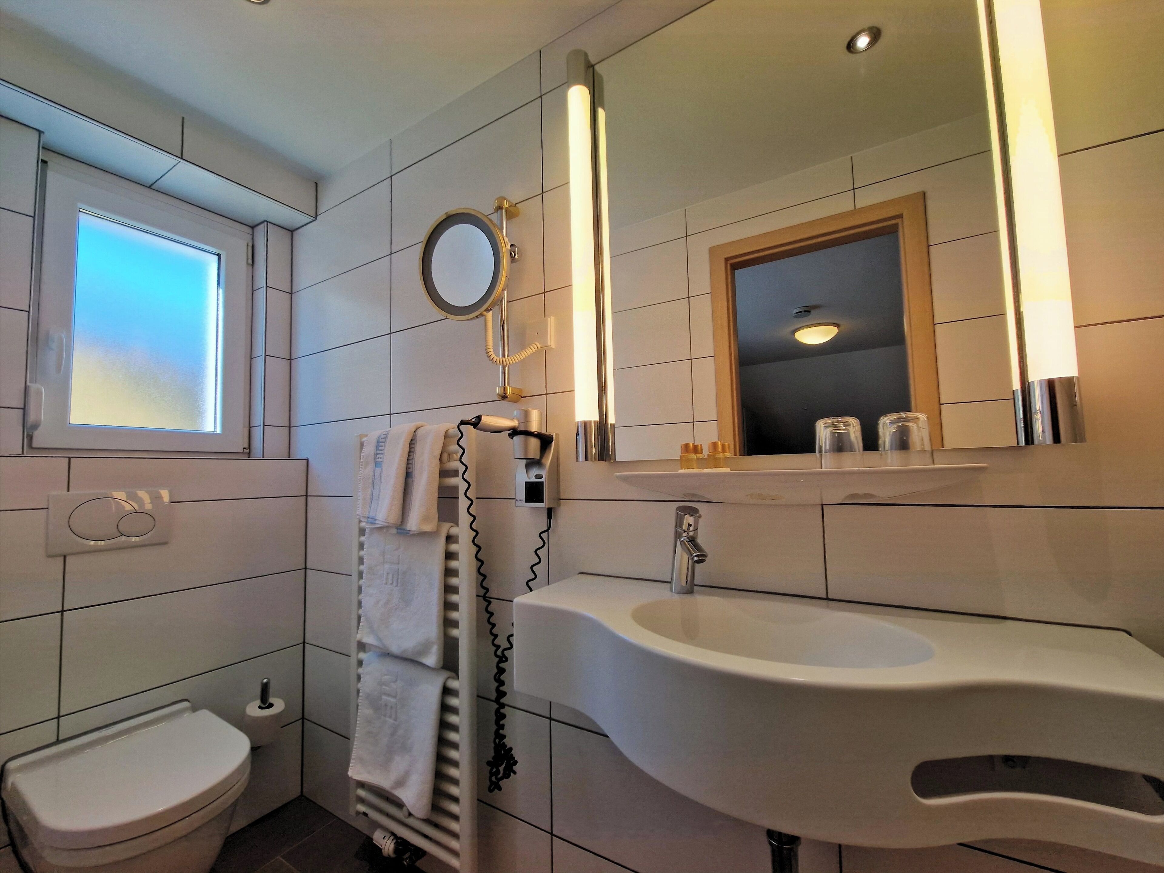 A modern bathroom with a toilet, sink, and towel rack.