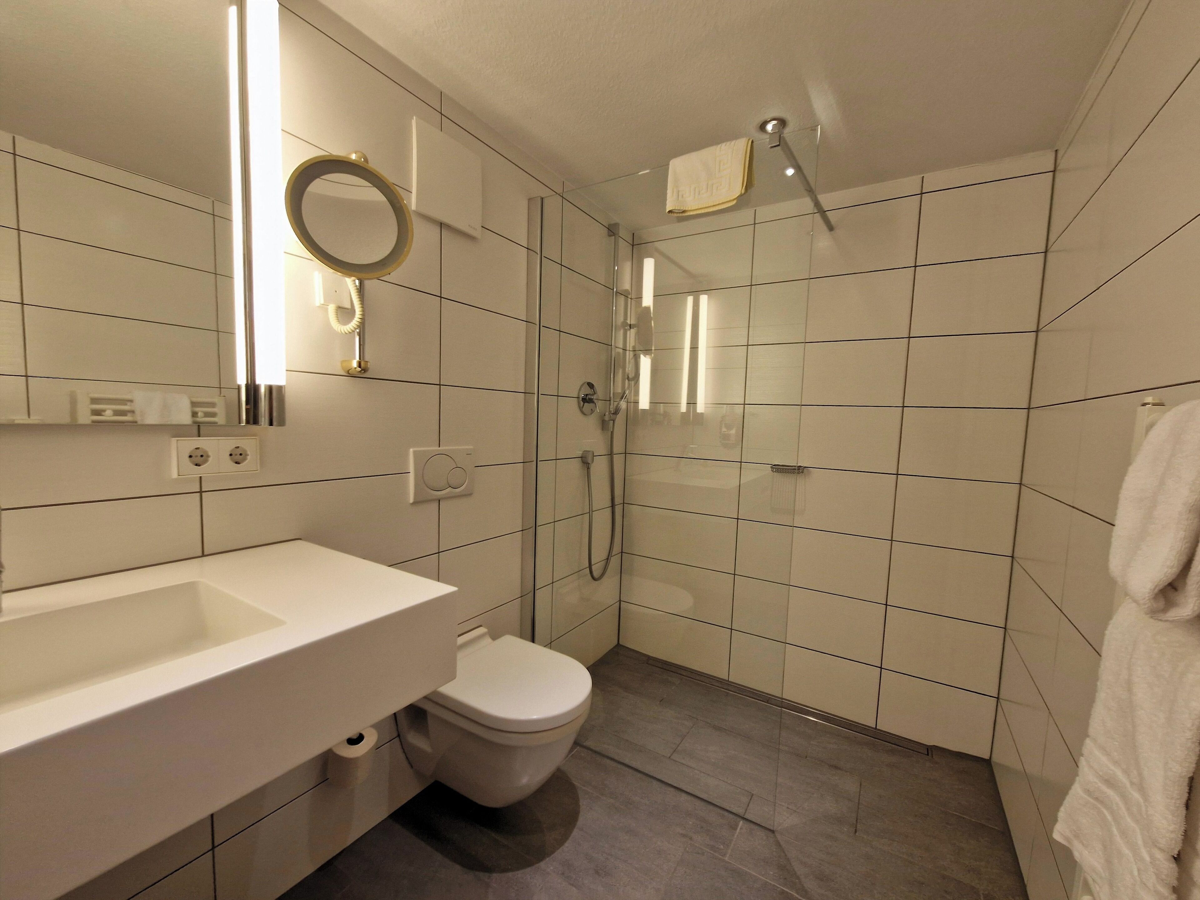 A modern bathroom with a white sink, toilet, and shower.
