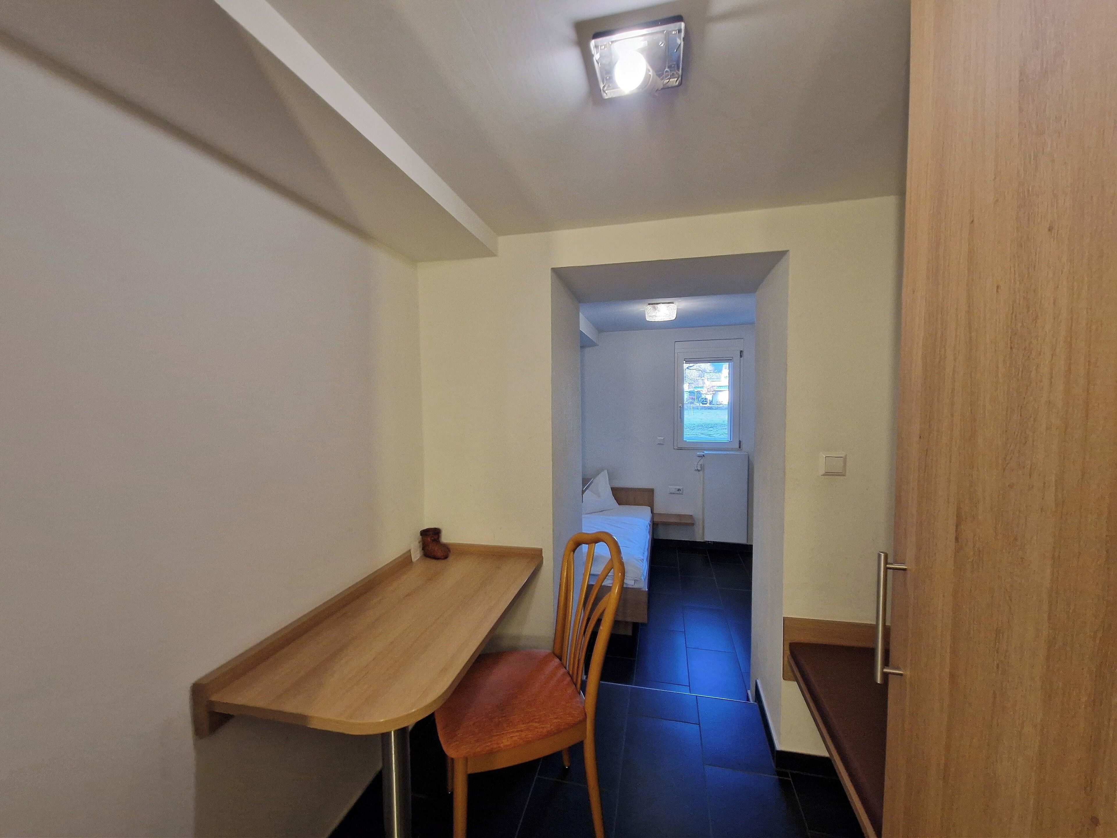 A compact room with a desk, chair, and a bed.
