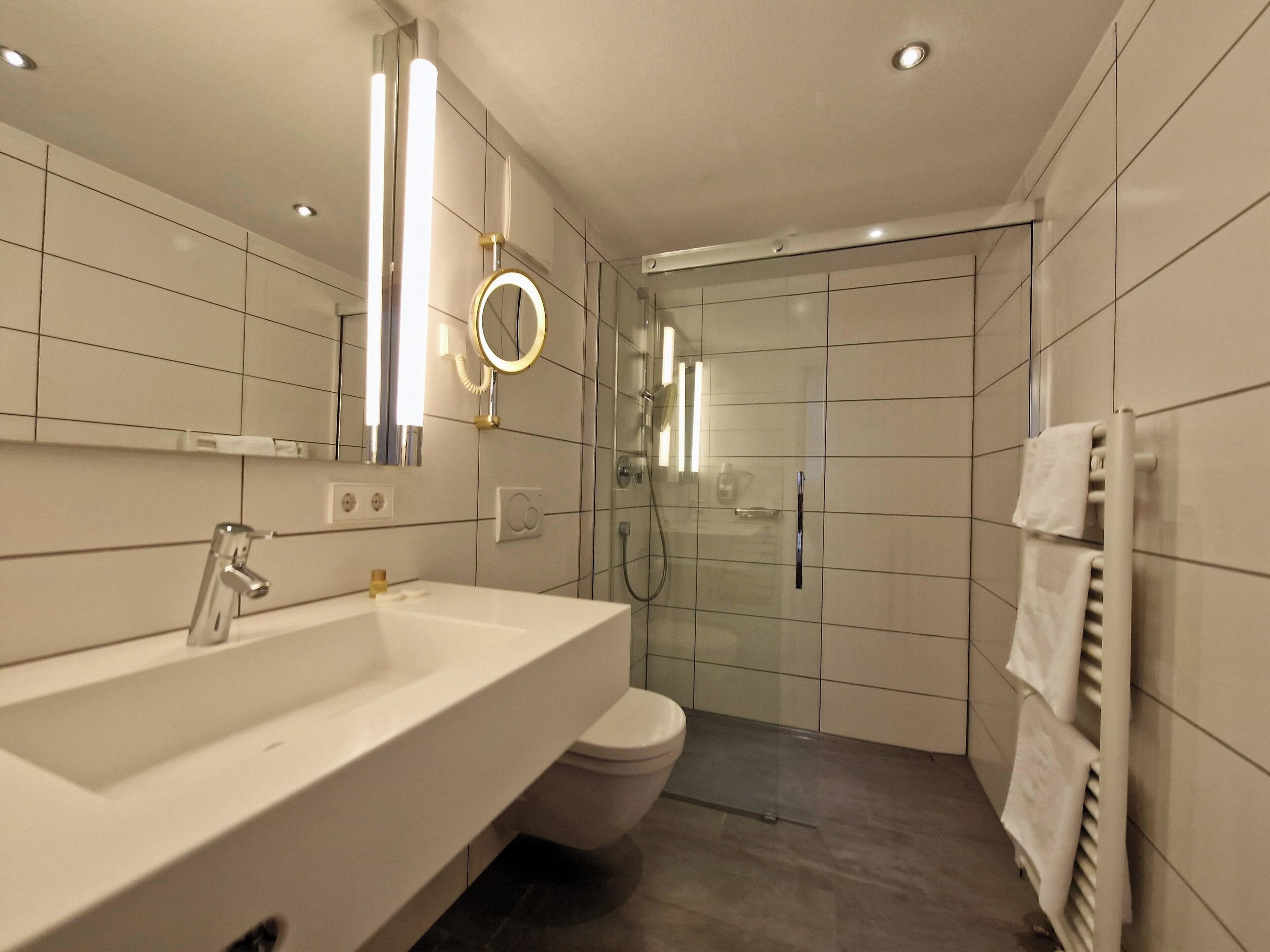 Une salle de bain moderne avec un grand lavabo, un miroir et une douche à parois de verre.
