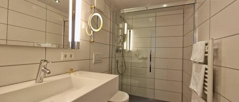 Une salle de bain moderne avec un grand lavabo, un miroir et une douche à parois de verre.