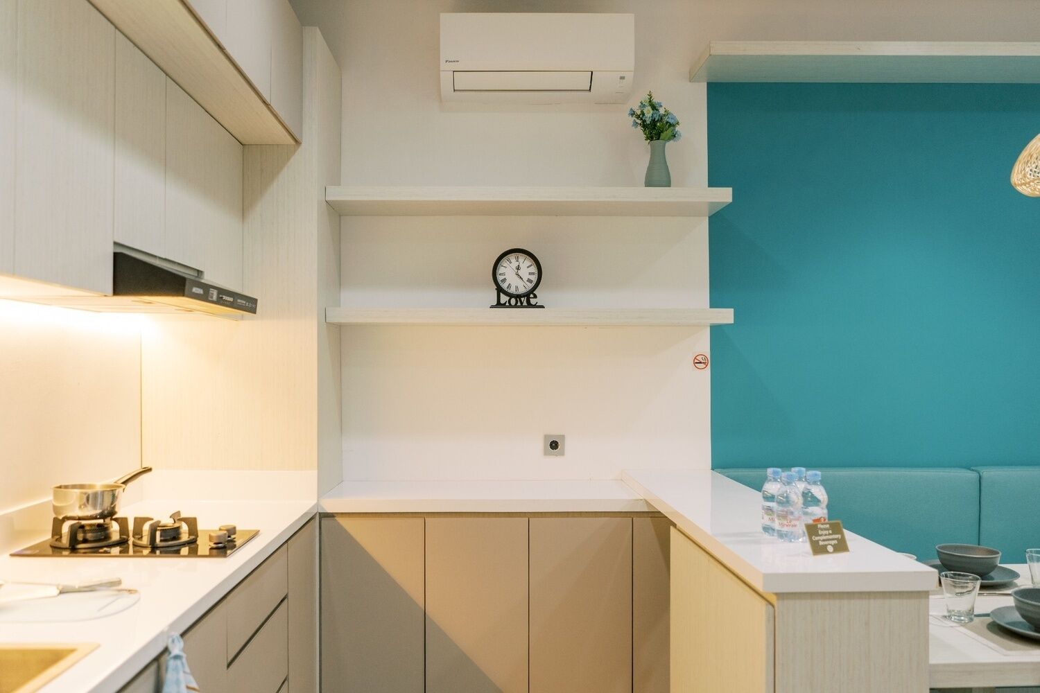 Una cocina moderna con armarios blancos, un reloj y una pared de acento color aguamarina.