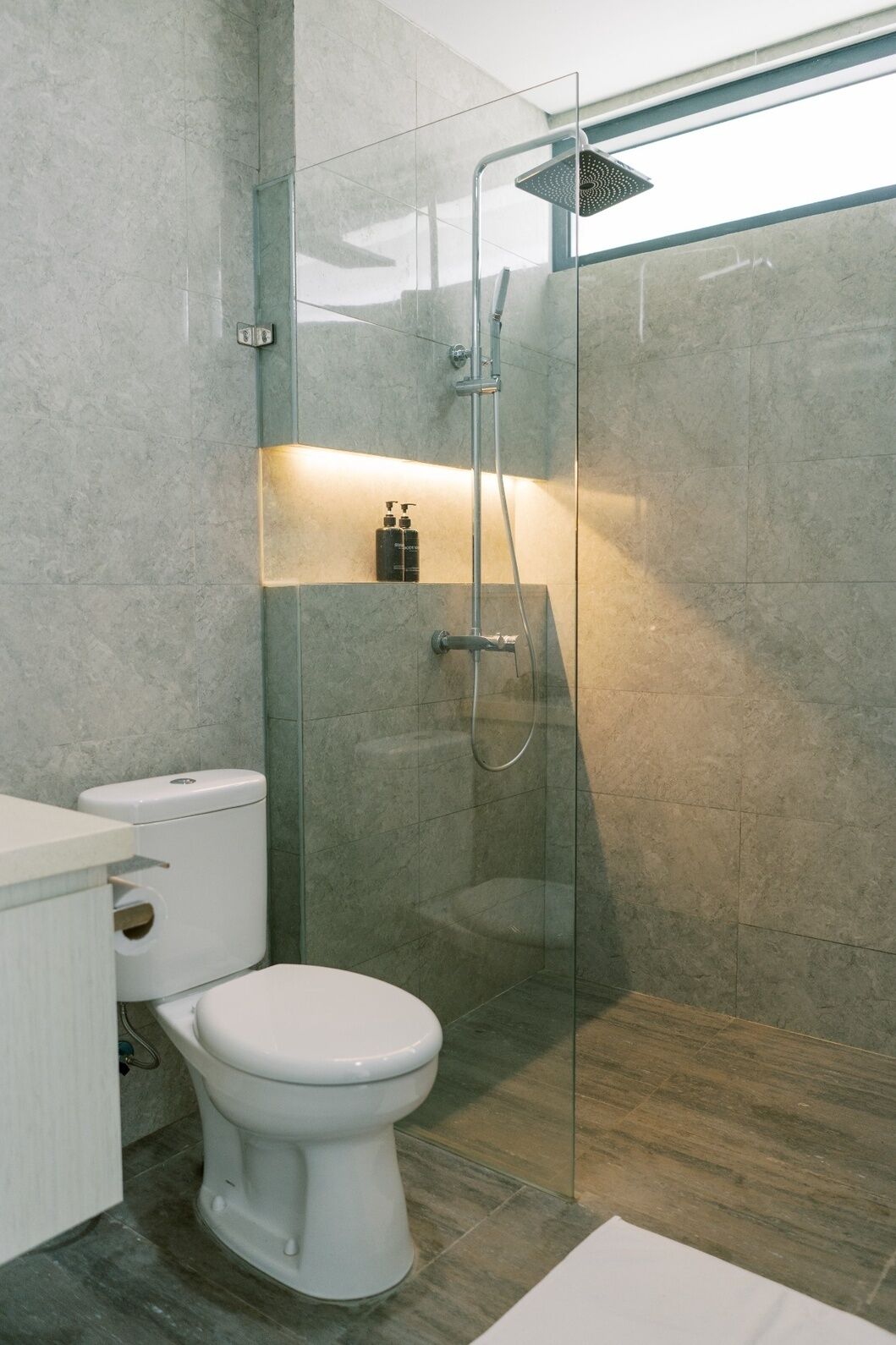A modern bathroom with a glass-enclosed shower, a toilet, and a sink.