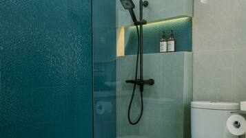 A modern bathroom with a glass shower enclosure, a toilet, and a shelf with toiletries.