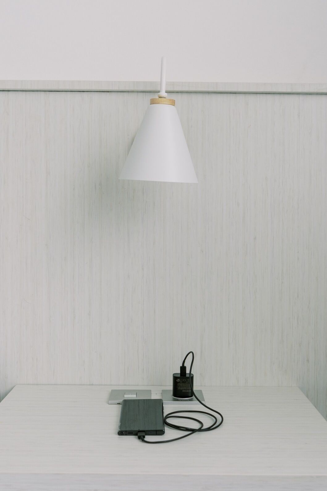 A white table with a lamp, a power strip, and a device on it.