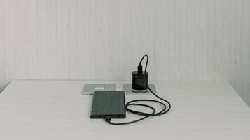 A white table with a lamp, a power strip, and a device on it.
