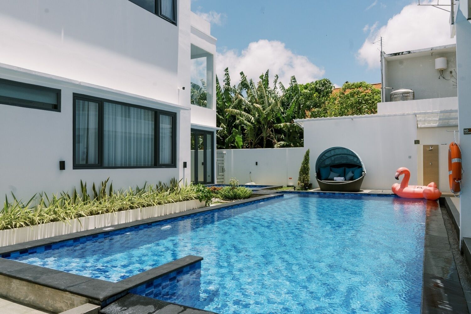 A modern pool area with a clear blue pool, a swan float, and a circular seating area.