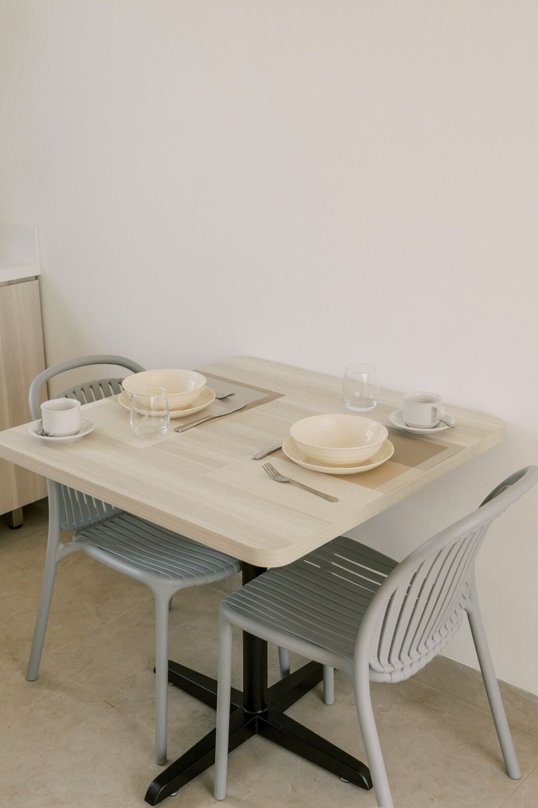 A dining table with two chairs, a bowl, a cup, and a glass.