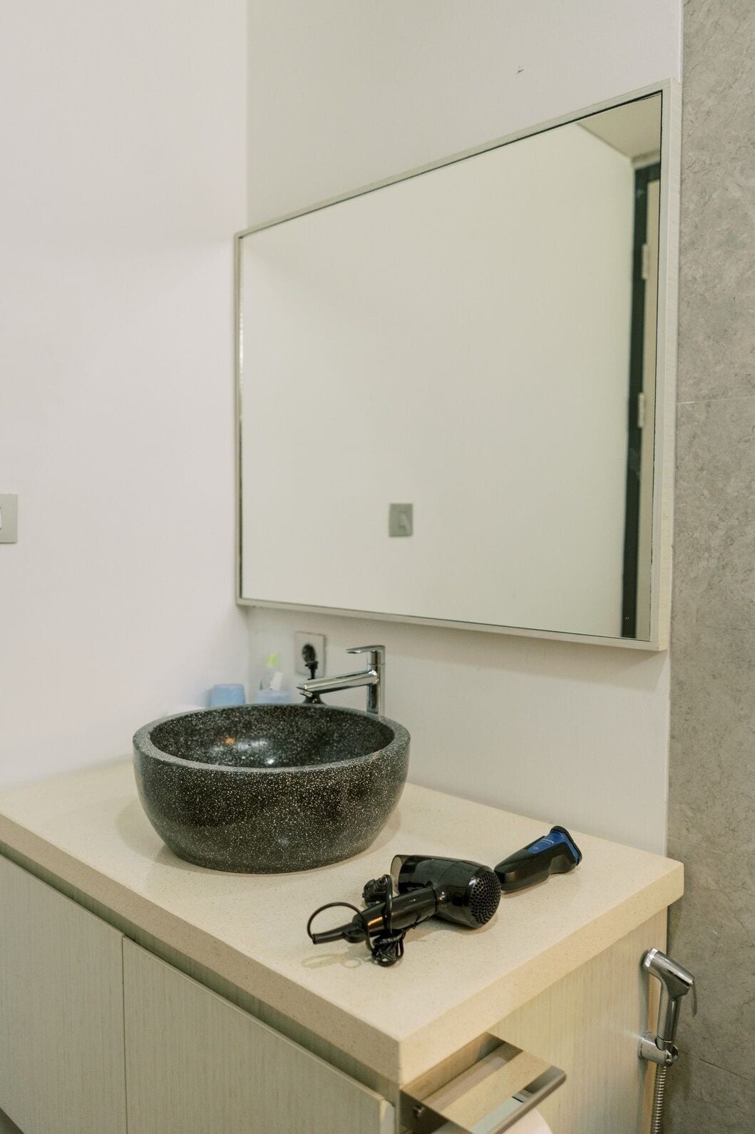 Un baño con lavamanos de piedra, espejo, secador de pelo y ducha.