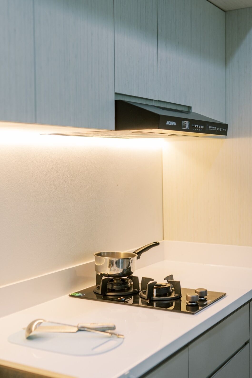 A kitchen with a gas stove, a pot, and a spoon on the counter.