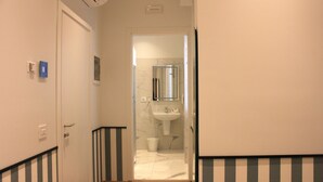 Un pasillo con paredes a rayas que conduce a un baño con lavamanos y espejo.