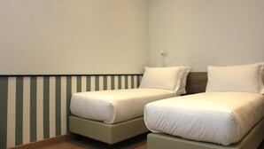 Una habitación con dos camas individuales, cada una con almohada y manta.