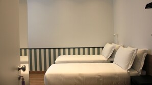 Un dormitorio con dos camas, suelo de madera, pared a rayas y una puerta con manija.