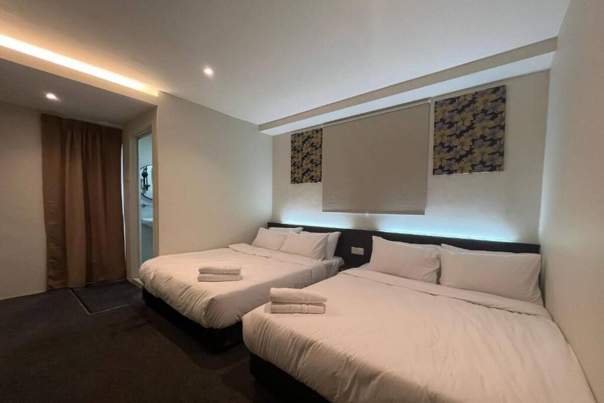 Une chambre d’hôtel avec deux lits, une grande fenêtre avec stores, une tête de lit et une œuvre d’art accrochée au mur.