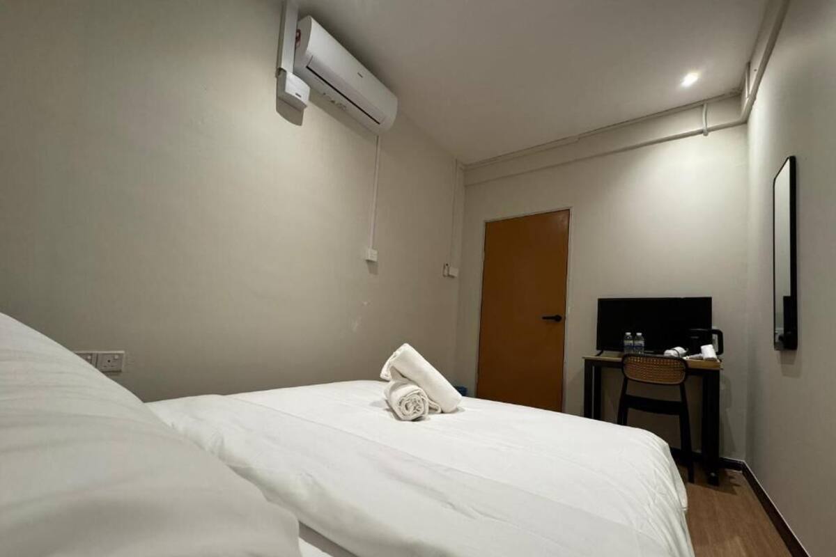 Une chambre d’hôtel équipée d’un lit, d’un bureau avec une chaise, d’une télévision et d’un appareil de climatisation.