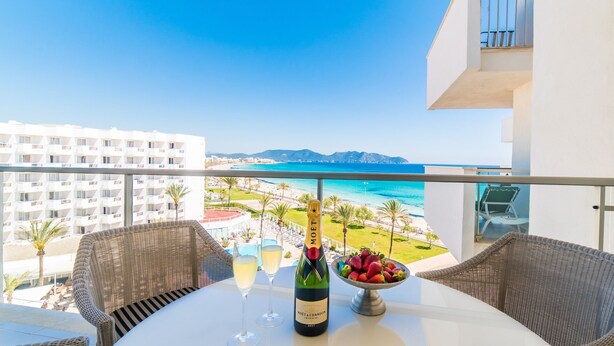 Ein Balkon mit Korbmöbeln, einem Tisch mit einer Flasche Moët & Chandon Champagner, zwei Gläsern und einer Schale Erdbeeren.