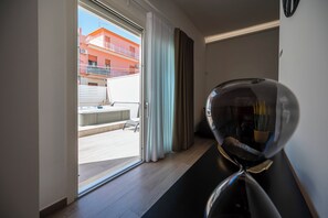 Ein modernes Hotelzimmer mit einer Schiebetür zum Balkon, einer kleinen Sitzecke und einem dekorativen Spiegel.