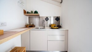 A compact kitchen with a wooden countertop, a stainless steel sink, and a small shelf with decorative items. - Mediterranea Suite (Avola)