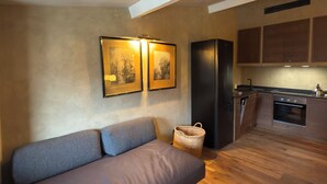 A modern living space with a sofa, a kitchen area, and wooden flooring. - In Downtown Florence above Santa Croce, the most beautiful church, renovated 2026 (Firenze)