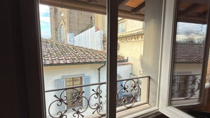 A room with a large window overlooking a courtyard with a tiled roof and a building with a stone facade. - In Downtown Florence above Santa Croce, the most beautiful church, renovated 2026 (Firenze)