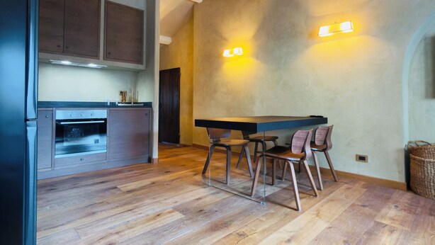 A modern kitchen with wooden cabinets, a built-in oven, and a dining area with a table and chairs. - In Downtown Florence above Santa Croce, the most beautiful church, renovated 2026 (Firenze)